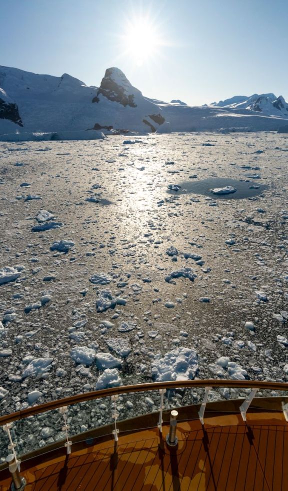 View of icebergs and mountains from a ship in Antarctica's pristine waters.