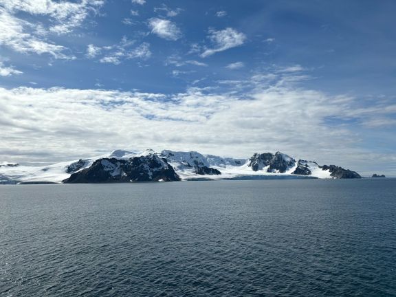 Breathtaking view of Antarctica's coastline with snowy mountains under a blue sky.