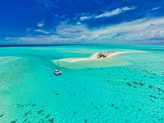Stunning aerial view of a sailboat near a pristine sandbar in Mauritius' turquoise waters.