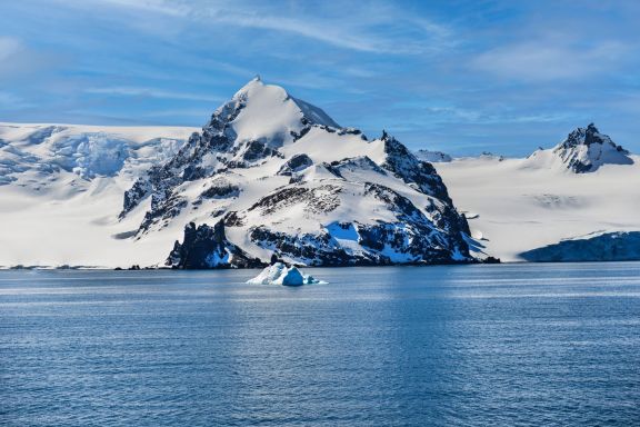 Stunning view of a snow-covered mountain and iceberg in Antarctica's icy waters.